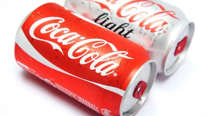 Een rood blikje Coca Cola en een lichtgrijs blikje Coca Cola Light